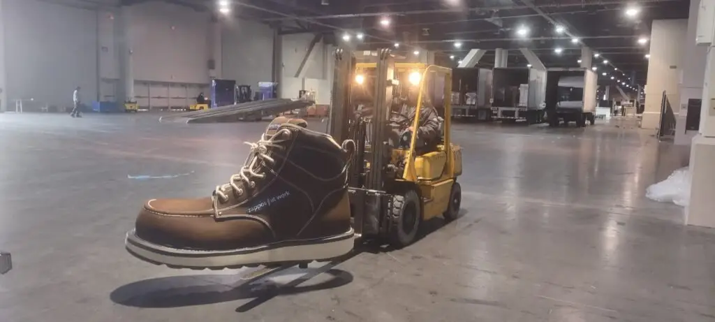 Forklift moving a large boot display from a moving helper